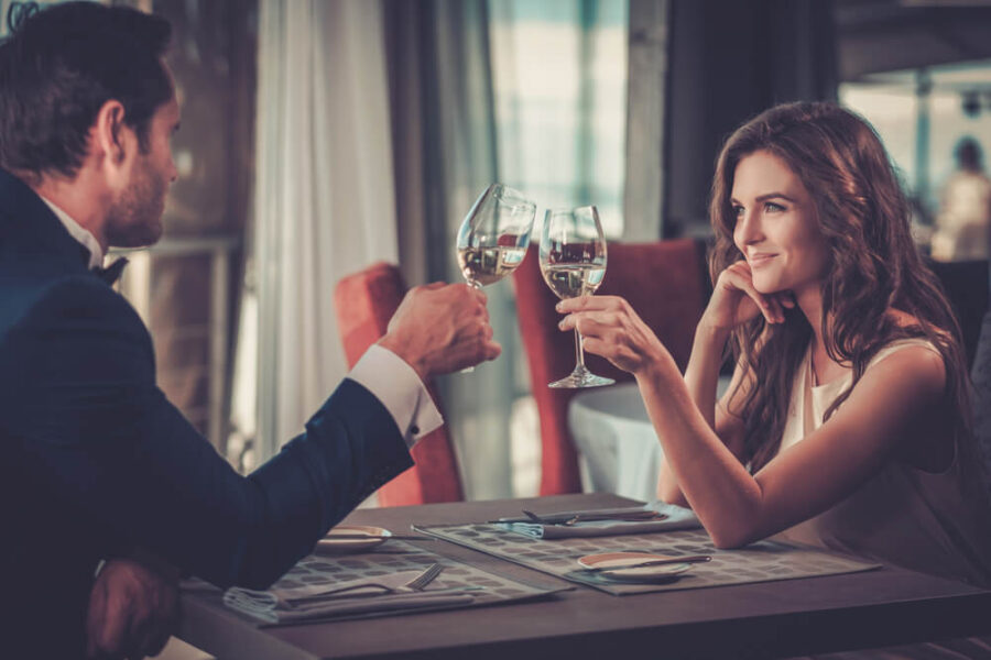 Man and woman at a restaurant each holding a glass of wine