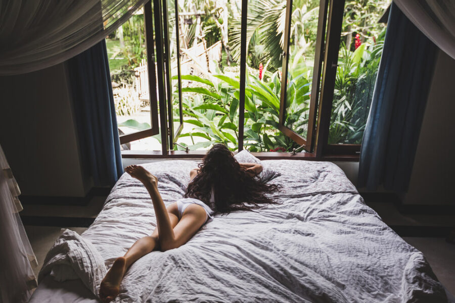 Woman laying on a bed looking out of a window